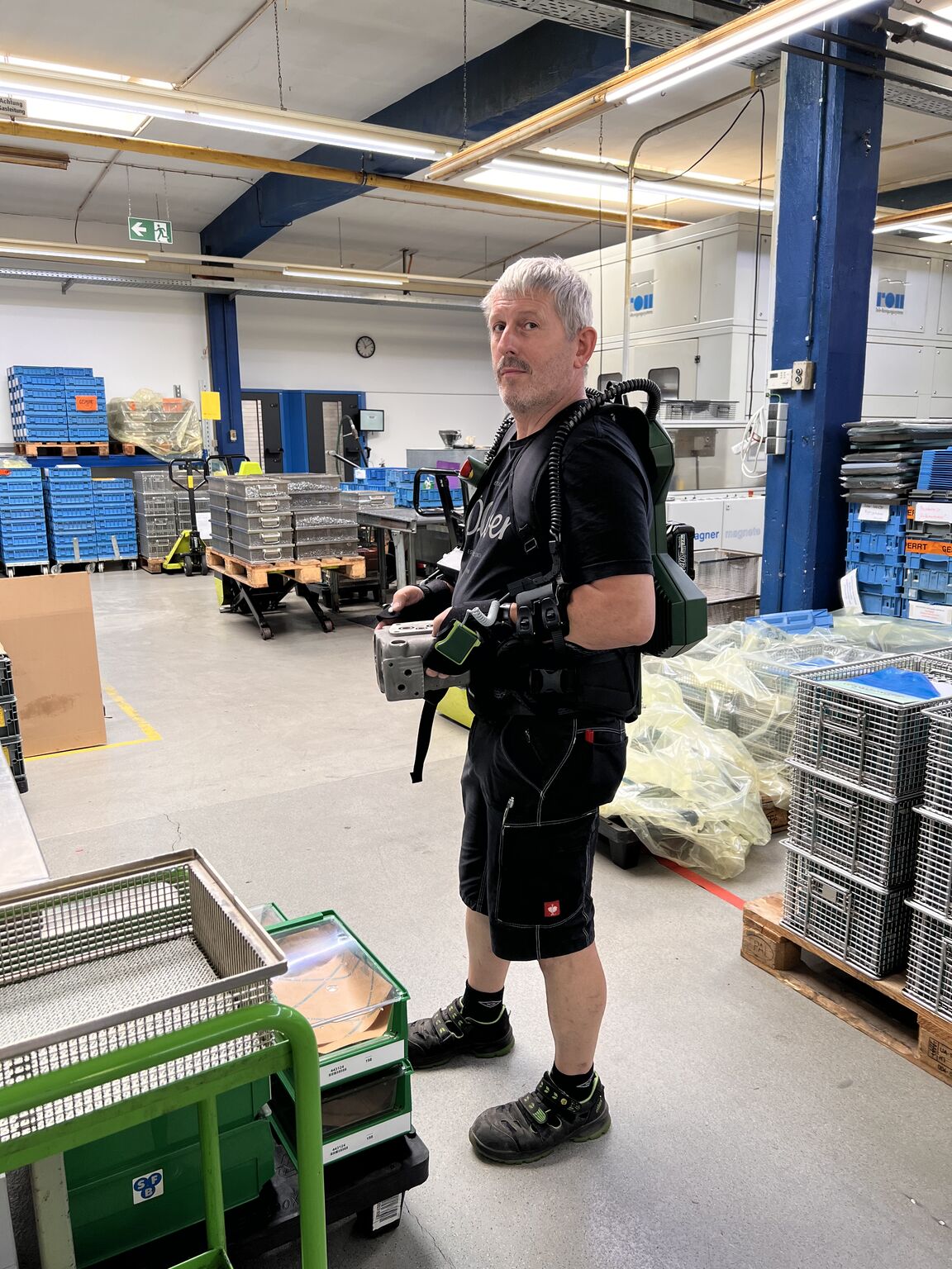 Ein Mitarbeiter von SFB testet das EASE Exoskelett im Produktionsalltag.